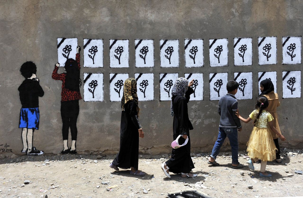 People pass by Murad Subay's mural "Flowers Bouquet" in Sanaa in May 2015. The Yemeni street artist has spent five years making the case for peace through street art projects.