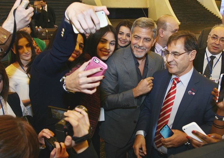 George Clooney stops to pose for selfies before participating in a panel discussion at the Second Global Forum Against Crime of Genocide.