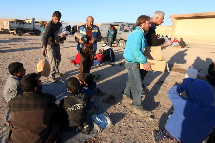 Volunteers from a Kurdish relief organization distribute food to displaced people, who are fleeing violence in Aleppo city and from Islamic State-controlled areas in Raqqa and Deir al-Zor, at a school in al-Mabroukeh village in the western countryside of Ras al-Ain, Syria December 28, 2015.