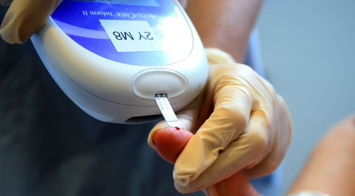 A nurse giving a patient a diabetes blood glucose test.