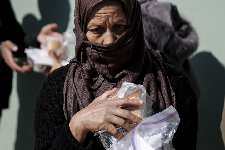 A migrant receives a portion of food and water during food distribution at a relocation camp in Schisto, near Athens, Greece,