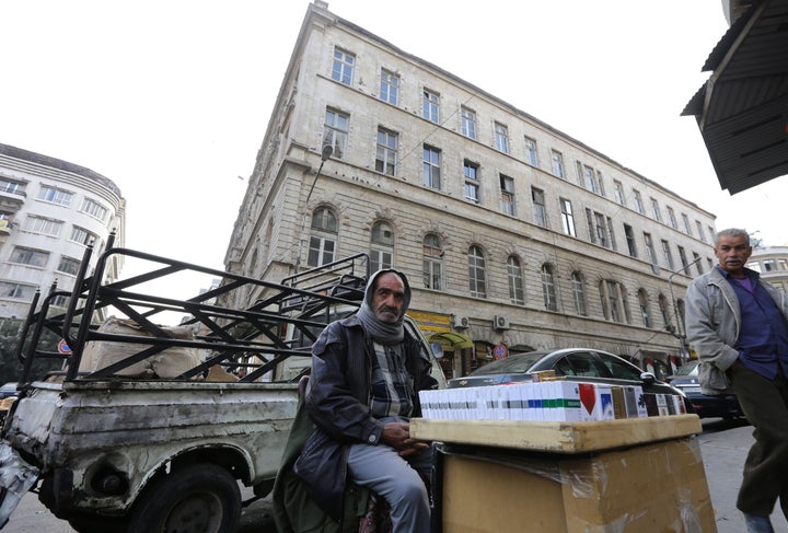 New government-imposed security regulations in Damascus are forcing the city's new arrivals to turn to bribery. A man sits in front of his pickup truck that also serves as his home in Damascus.