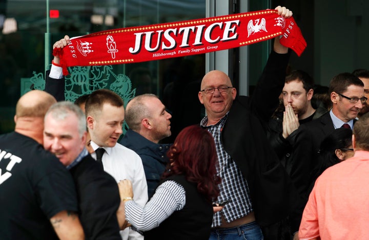 Relatives hold up a scarf after the jury delivered its verdict at the new inquests into the Hillsborough disaster, in Warring
