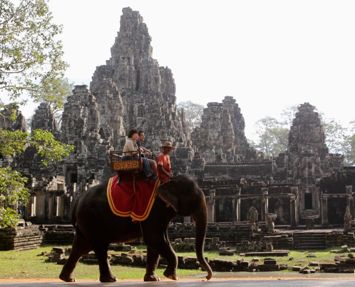 Tourists ride an elephant past the ruins of Cambodia's Bayon temple in Siem Reap, December 22, 2012.