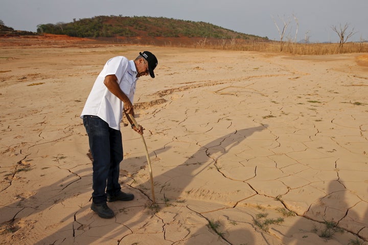 Drought has severely reduced water levels at Venezuela's main dam and hydroelectric plant in Guri, Bolivar state. The country's electricity minister Luis Motta places a wooden stick on the ground of previously submerged land in Guri.