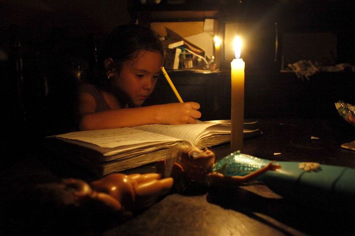 The country is suffering a brutal recession, shortages of water and basic supplies, and electricity cuts. A child does her homework by candlelight in San Cristobal.