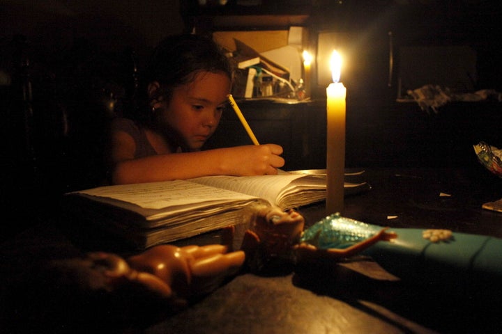 The country is suffering a brutal recession, shortages of water and basic supplies, and electricity cuts. A child does her homework by candlelight in San Cristobal.