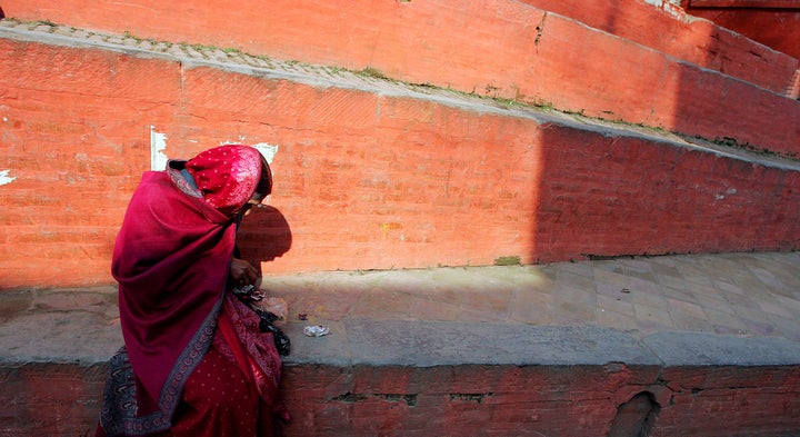 A woman sits at the steps of a Hindu temple in Kathmandu February 5, 2005.