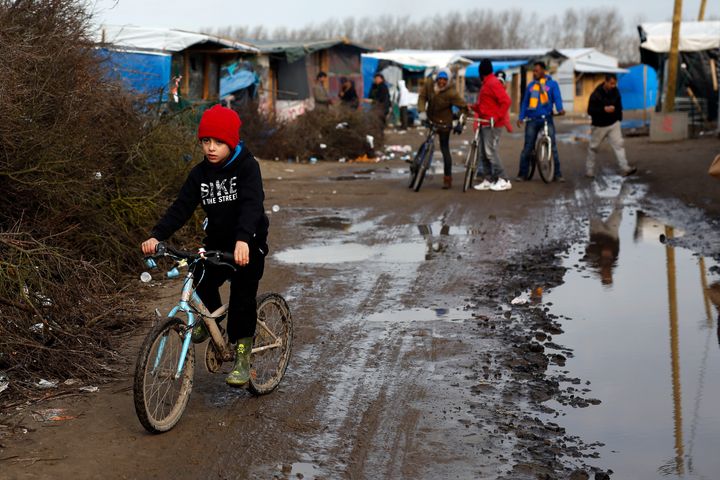 A child rides his bicycle in a makeshift camp near Calais, France