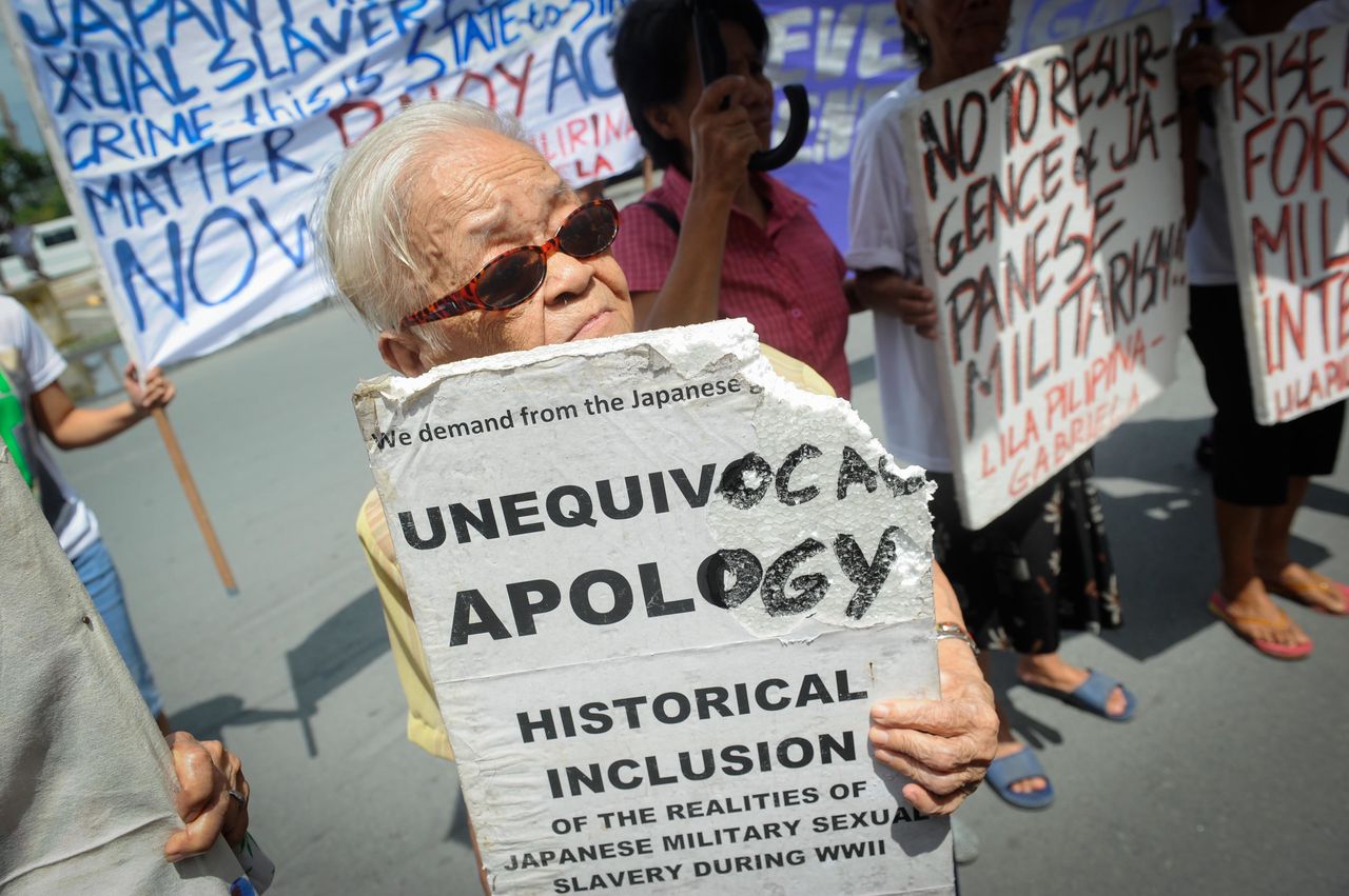 Remedios Pecson holds a sign at a protest in front of the Japanese Embassy on Aug. 14, 2015. Pecson, then 80 years old, carried a walking stick and was supported by fellow protesters during the rally.