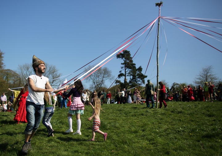 People dance around the maypole used in a Beltane May Day celebration below Glastonbury Tor on May 1, 2013 in Glastonbury, En
