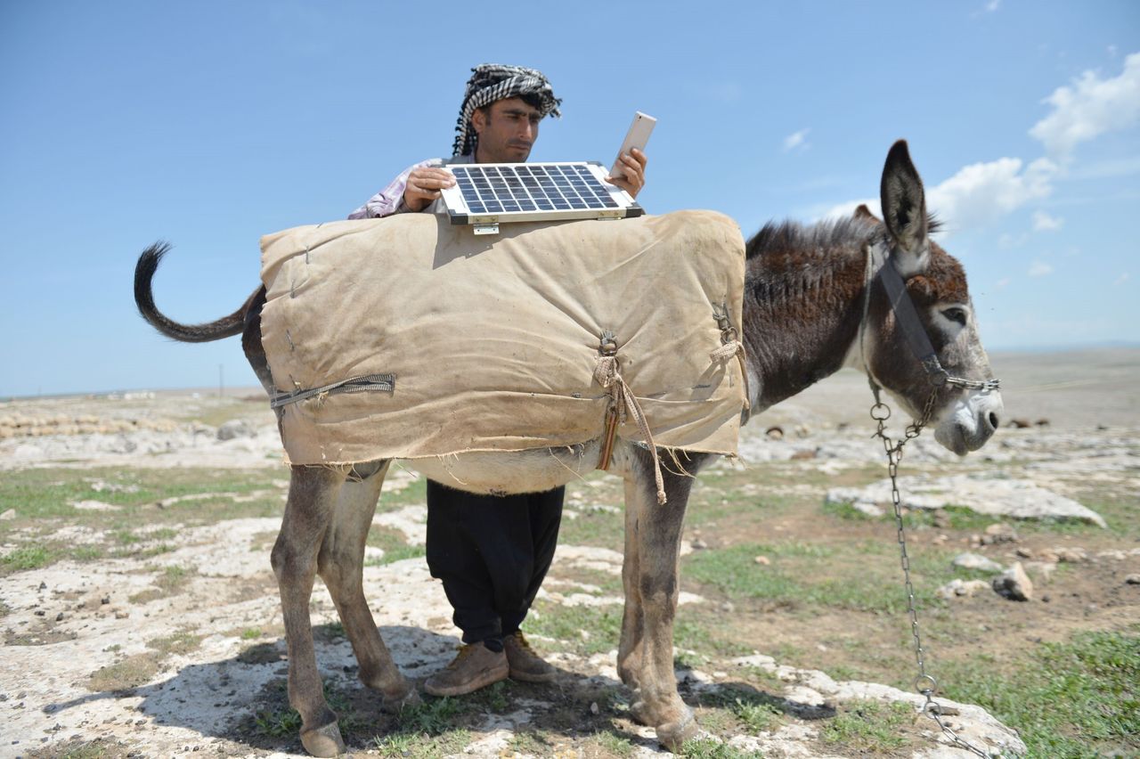 A shepherd in Turkey charges his phone using solar panels.