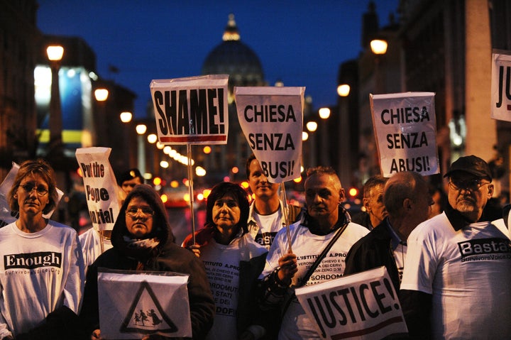 Parents and victims of priest abuse from around the world hold banners during a demonstration in Rome in front of the Vatican dome on October 31, 2010.