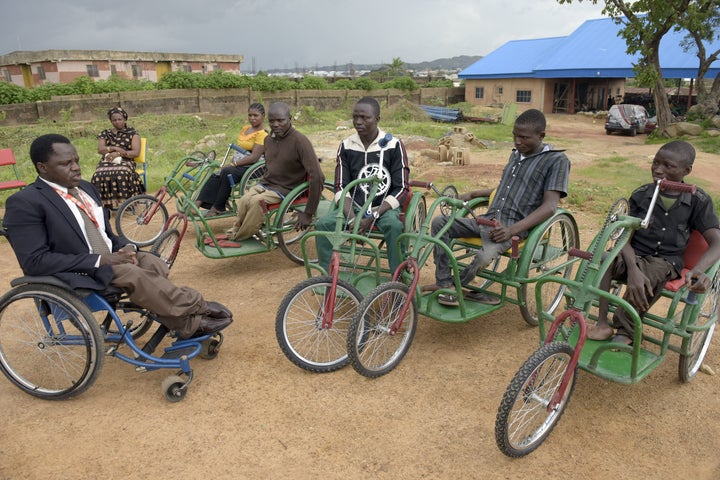 Founder of Beautiful Gate Handicapped People's Centre Ayuba Gufwan (L) speaks to handicapped recipients of his new wheelchair at the centre in Jos, northcentral Nigeria Plateau State, on July 16, 2015. Ayuba Gufwan deals with the aftermath of the disease to improve the lives of Nigerian polio survivors who have had to cope with a lifetime of hardship in a society ill-adapted for the disabled. At his workshop, 49 staff -- seven of them polio survivors like him -- and 17 young apprentices spend the day bending, sawing, bashing and welding metal. AFP PHOTO/PIUS UTOMI EKPEI (Photo credit should read PIUS UTOMI EKPEI/AFP/Getty Images)