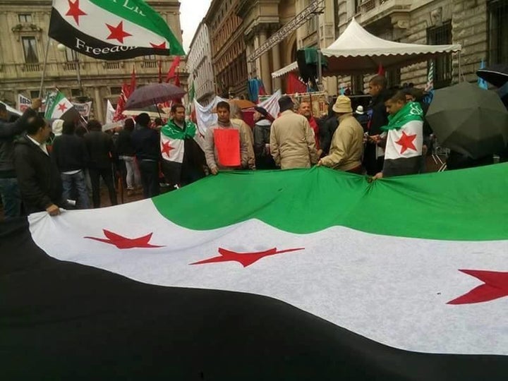 People around the world united in protest to highlight the atrocities done to the civilians under attack from government shelling and airstrikes in Aleppo. Demonstrators hold the Syrian opposition flag in Milan, Italy.