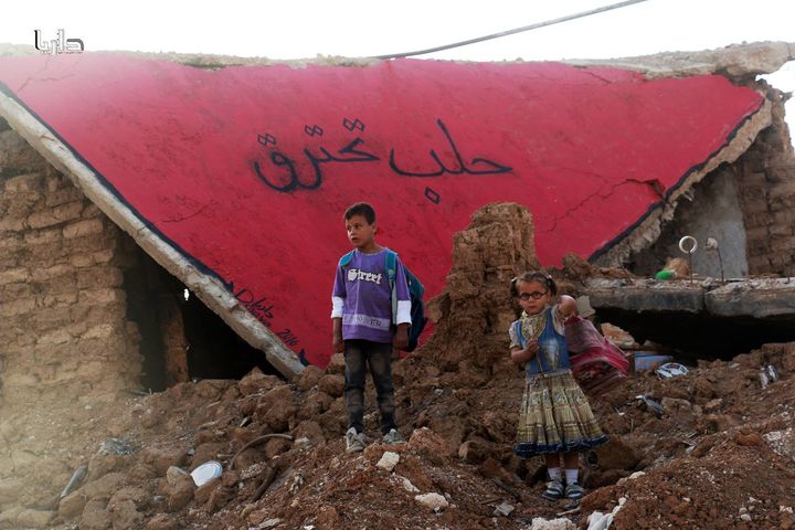The organizers hoped the protests would help pressure Assad's government and its allies to stop bombarding civilian areas. Children stand in front of a building, painted red and with "Aleppo is Burning" written on it, in Daraya, Syria.