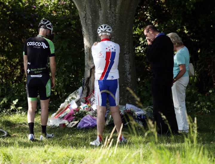 Cyclists look at floral tributes to Donald Lock at the scene