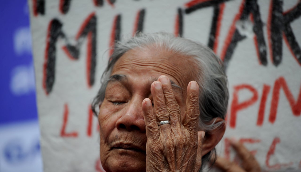 A Filipina "comfort woman" wipes away a tear during a January protest in Manila. Over 1,000 women and girls were captured and imprisoned in "rape camps" in the Philippines by the Japanese military during World War II.