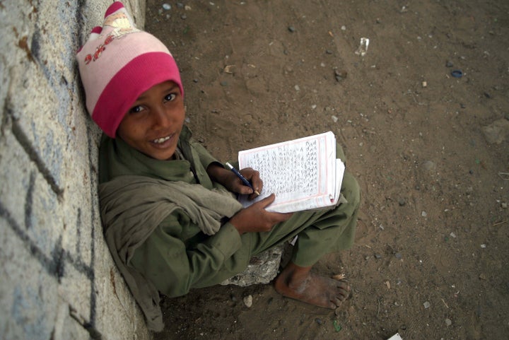 A Yemeni young boy poses as he writes in an exercise book sitting outside a minibus (unseen) turned into a mobile classroom on February 11, 2014 in the capital Sanaa. The 'Mobile school' project started from a youth initiative in 2013 and offers education to children of the street with the help of volunteer teachers. AFP PHOTO/ MOHAMMED HUWAIS (Photo credit should read MOHAMMED HUWAIS/AFP/Getty Images)