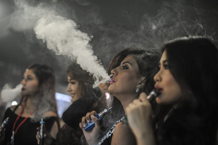 Promoters smoke electronic cigarettes during the VapeFair in Kuala Lumpur on December 5, 2015.