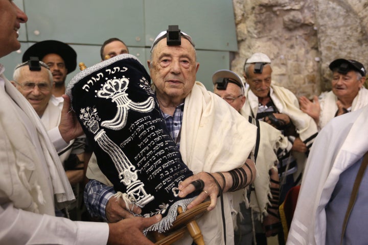 A Jew carries the Torah scroll.