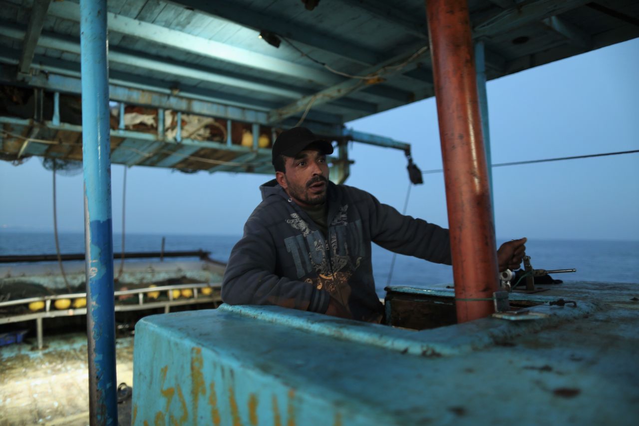 Raed Abu Owda prepares to lift the fishing nets with the levers of the ship. 