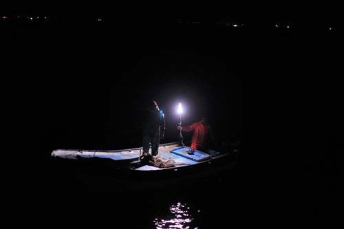 Palestinian fishermen sail around their fishing nets to protect them from other ships.
