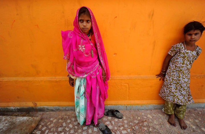 In this Friday, May 6, 2011 photo, a newly married child bride, left, stands at a temple in Rajgarh, about 155 kilometers (96 miles) from Bhopal, India. Ignoring laws that ban child marriages, several young children, are still married off as part of centuries-old custom in some Indian villages. India law prohibits marriage for women younger than 18 and men under age 21. (AP Photo/Prakash Hatvalne)