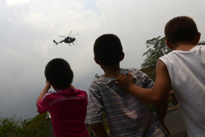 Children watch a helicopter carrying a military unit in Soyapango, El Salvador, on April 26, 2016. El Salvador has the highest homicide rate of any peacetime country in the world.