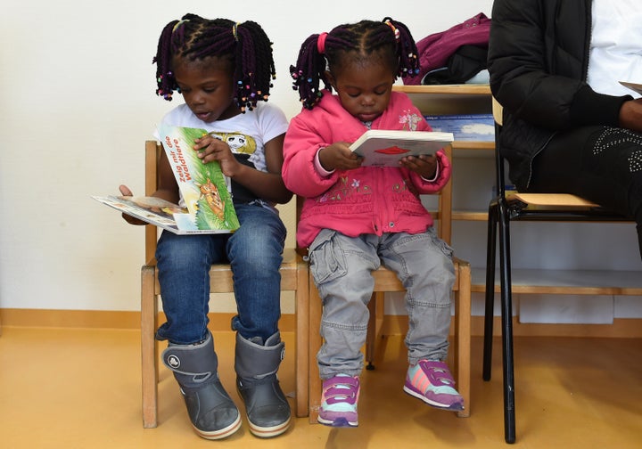 Refugee children from Nigeria read books during a first event of the three-year program 'reading start for refugee children' in the refugee camp 'Bayernkaserne' in Munich, southern Germany, on March 21, 2016. During the program which starts on behalf of the German Federal Ministry of Education and Research, refugee children up to five year receive a reading start set with an age-appropriate book. / AFP / CHRISTOF STACHE (Photo credit should read CHRISTOF STACHE/AFP/Getty Images)