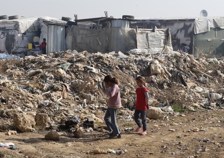 Girls walk near garbage inside Fayda Syrian informal refugee camp in Zahle, Lebanon December 26, 2015. REUTERS/Mohamed Azaki