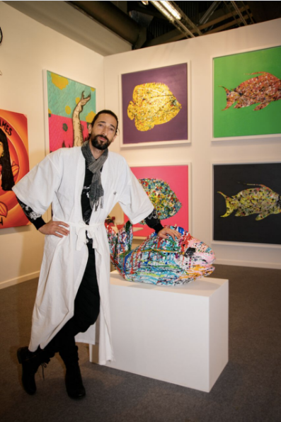 Brody with his art, which "calls upon the viewer to find light in a dark world through a collection of lively, colorful painted fish."