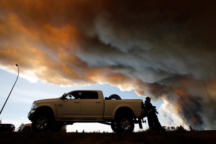 People wait at a roadblock as smoke rises from wildfires near Fort McMurray, Alberta, Canada, May 6, 2016.