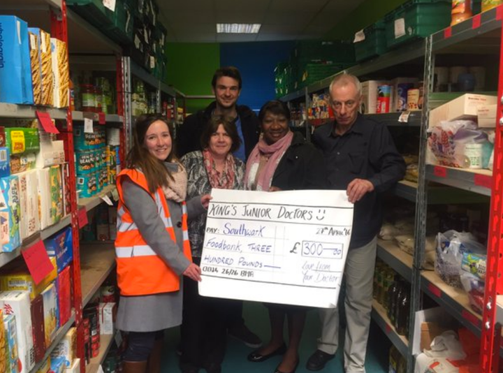 A junior doctor poses with foodbank staff as a cheque for £300 - made up of other medics' donations - is gifted