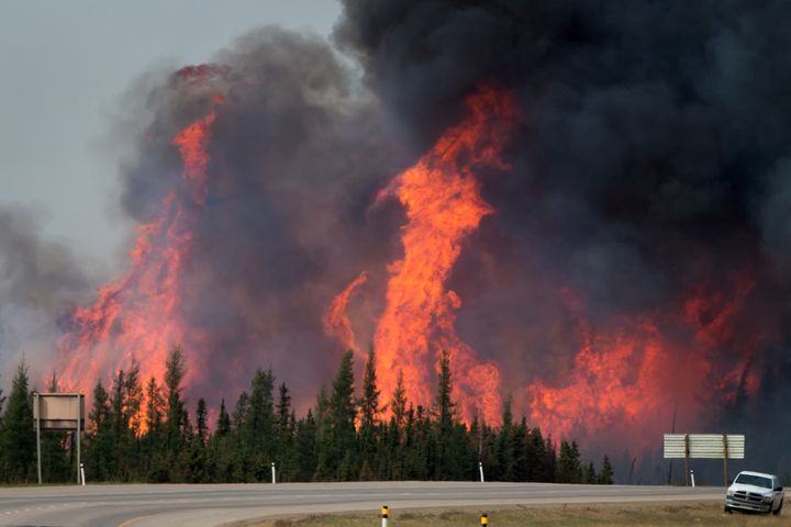 A wildfire burns behind abandoned vehicles on the Alberta Highway 63 near Fort McMurray, Alberta, Canada, on Saturday