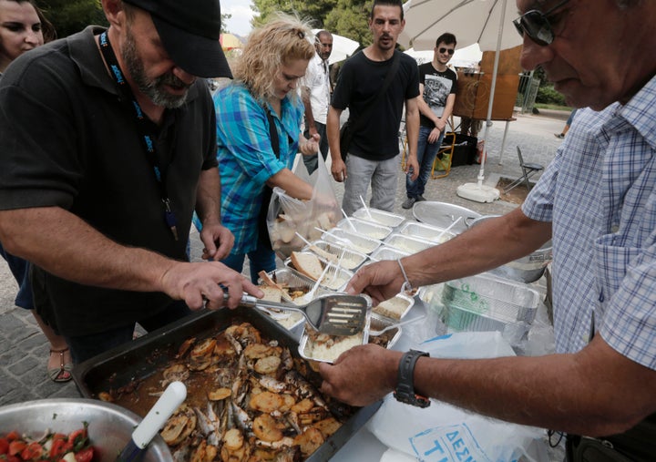 Constantinos Polychronopoulos, left, distributes food portions at a soup kitchen.