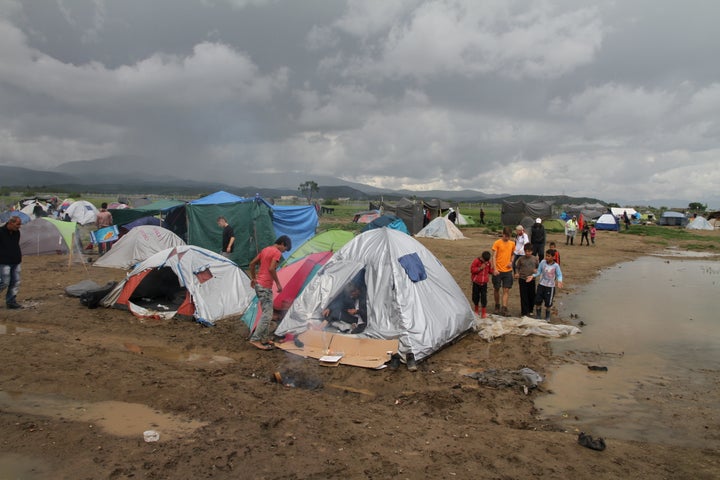 A photo taken at the Idomeni refugee camp on the morning of the ceremony shows the dire conditions endured by the 12,000 peop