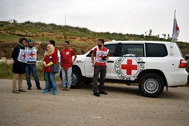 ICRC officials watch as a truck from the Red Crescent and International Committee of the Red Cross (ICRC) carrying international aid crosses arrives in the rebel held village of Teir Maalah, on the northern outskirts of Homs, as they make their way to Al-Rastan, north of the central Syrian city of Homs, on April 21, 2016. The Red Crescent and International Committee of the Red Cross will deliver the aid to some 120,000 civilians in and around the Homs province town of Rastan, ICRC spokesman Pawel Krzysiek told AFP. / AFP / MAHMOUD TAHA (Photo credit should read MAHMOUD TAHA/AFP/Getty Images)