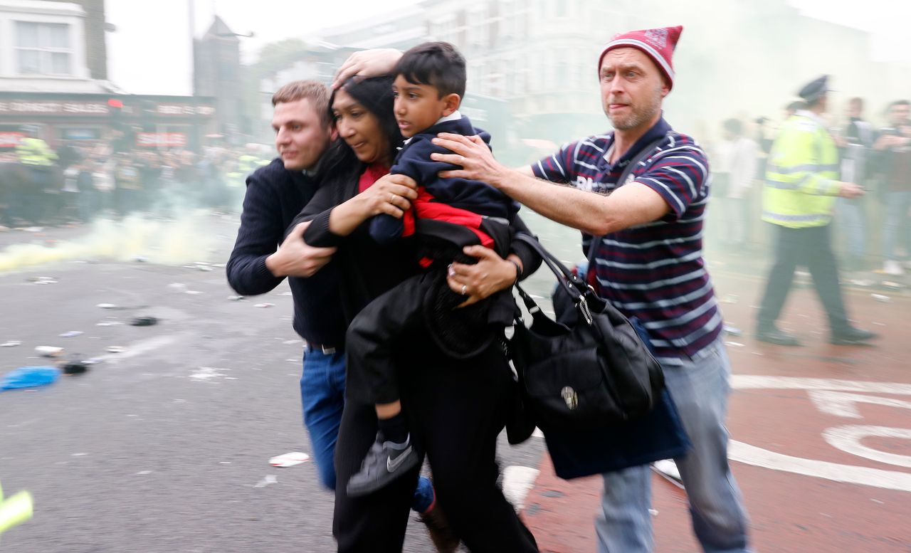 Football fans run for cover as the Manchester United team bus is pelted with objects as it enters Upton Park in London 