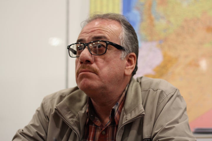 Ahmed al Rumeh, an outspoken critic and writer from Damascus, sits in front of a map of Syria during an interview in the Turk