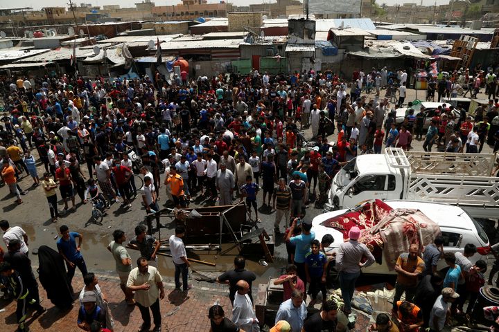People gather at the scene of a car bomb attack in Baghdad's mainly Shi'ite district of Sadr City, Iraq.