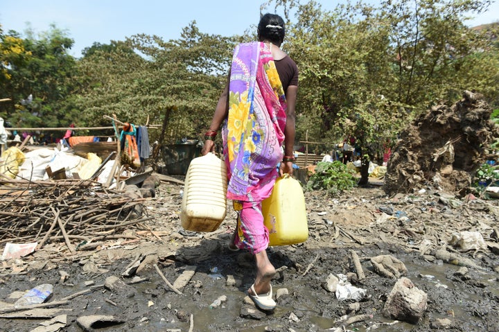 An Indian woman carries containers filled with drinking water at a makeshift camp in Mumbai. Some 300 families who have migra