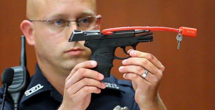 Sanford police officer Timothy Smith holds up the gun used by George Zimmerman to kill Trayvon Martin during the 2013 trial that led to Zimmerman's acquittal. 