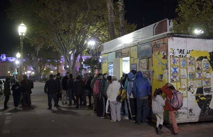 Homeless people and others in need gather to get food and clothes at the stall with a so called 'social fridge' of the Red Solidaria in Buenos Aires on April 29, 2016.