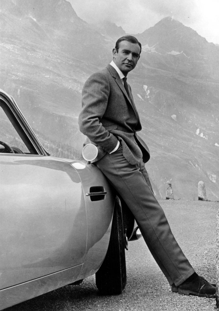 Connery as James Bond, posing next to his Aston Martin DB5 in a scene from "Goldfinger."