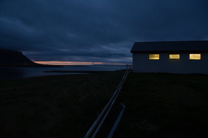 A warm glow comes from the cow barn at Hraunhals during the evening milking.