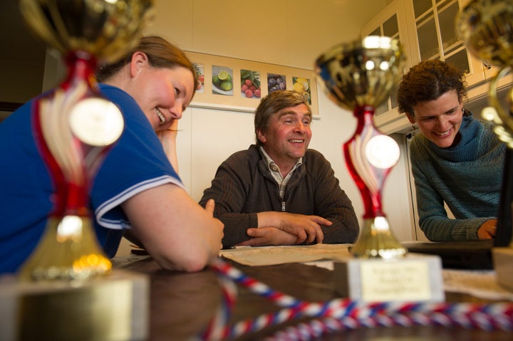 Lauga, Eyberg and Jennifer Kingsley share stories amid farming trophies spread across the kitchen table.