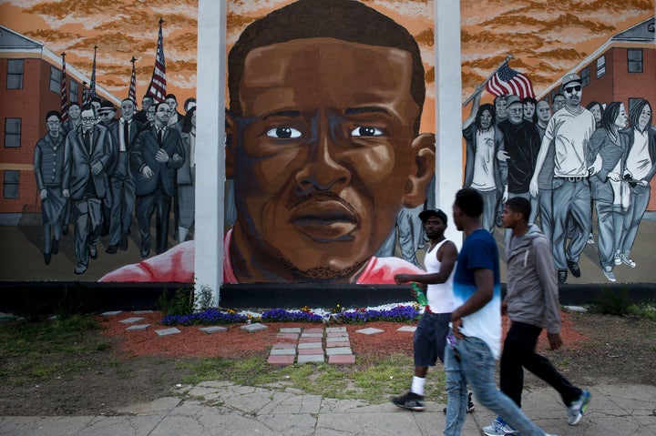 People pass a mural depicting Freddie Gray in Baltimore a year after the protests that were sparked by Gray's death in police custody.