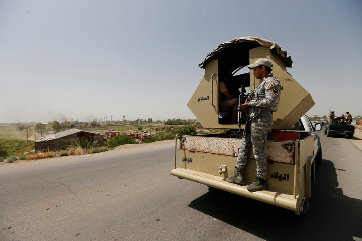 Shi'ite fighters loyal to radical cleric Muqtada al-Sadr, stand guard on a road after a bomb attack in Baghdad's northern outskirts, Iraq May 15, 2016.