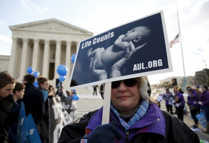 A protester holds up a sign in front of the U.S. Supreme Court on the morning the court takes up a major abortion case focusi
